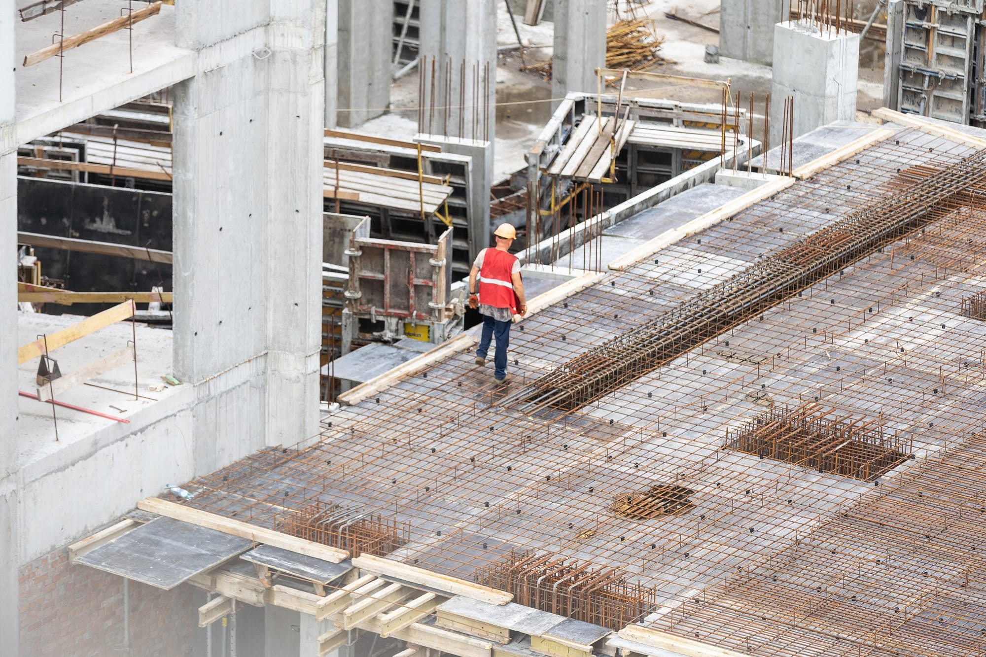Lone worker crossing a rebar deck on a concrete frame, the kind of progress RDrive tracks