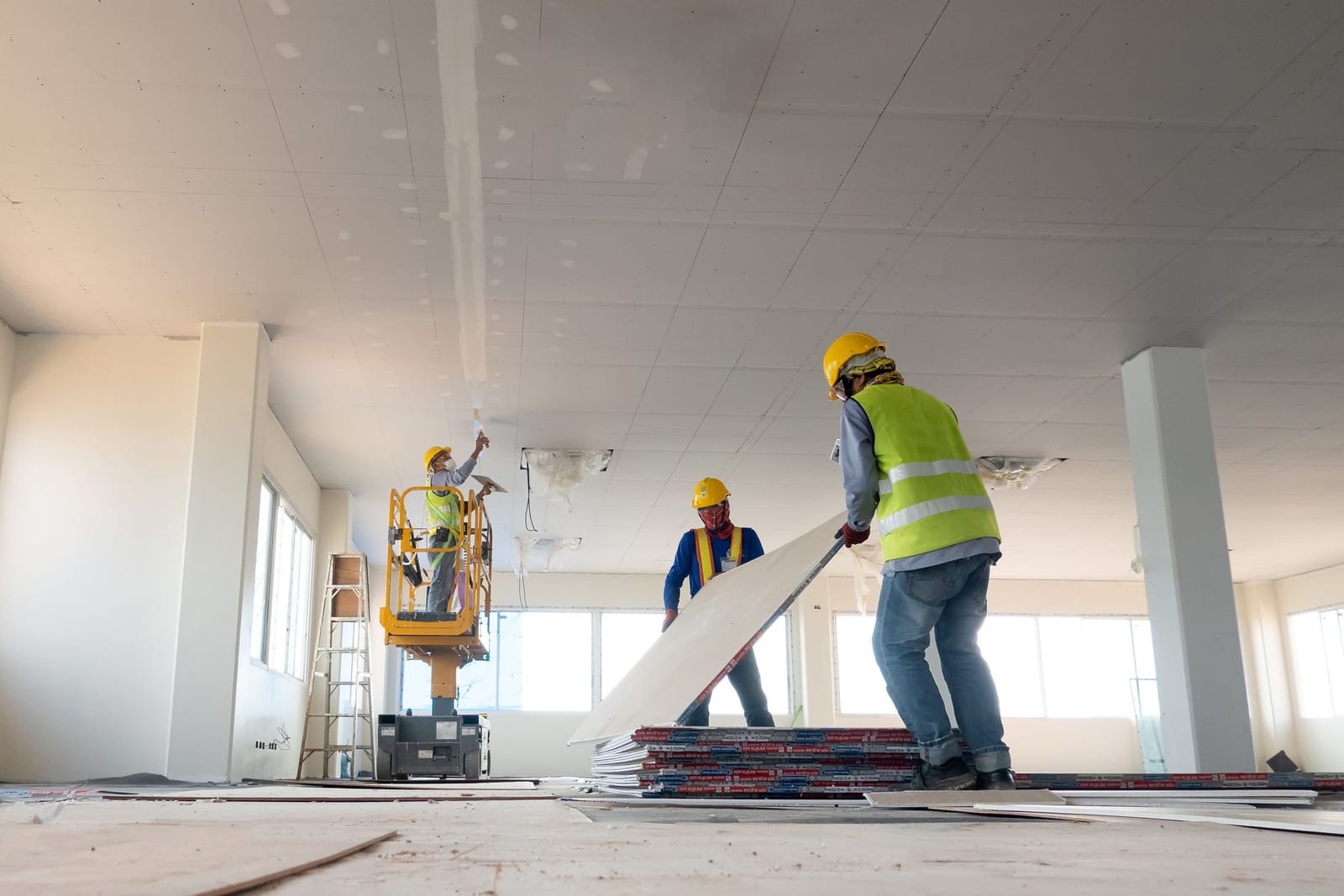 Subcontractors fitting plasterboard in an interior fit-out, the trade work RDrive records