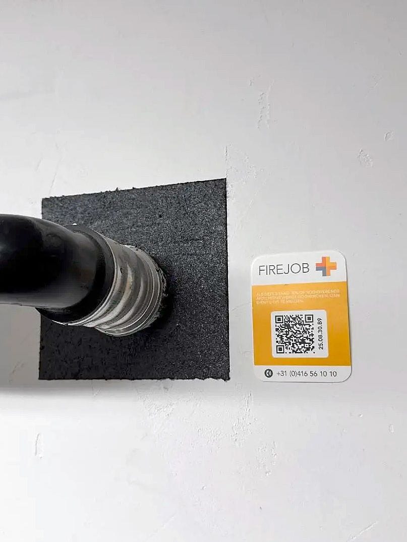 FIREJOB QR label beside a single fire-sealed pipe penetration, linking the seal to its digital record