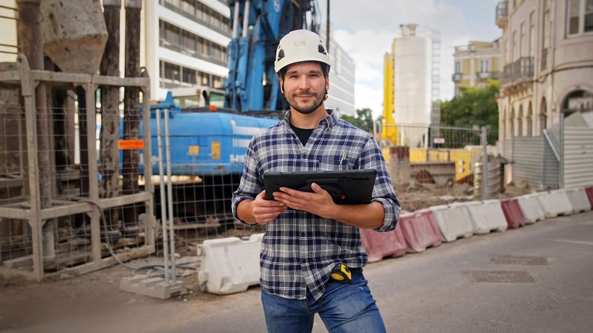Engineer holding a tablet beside an urban construction site, keeping the project record for the long term