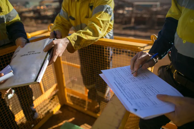 Site workers signing paper permits by hand, the manual process RDrive permit management replaces