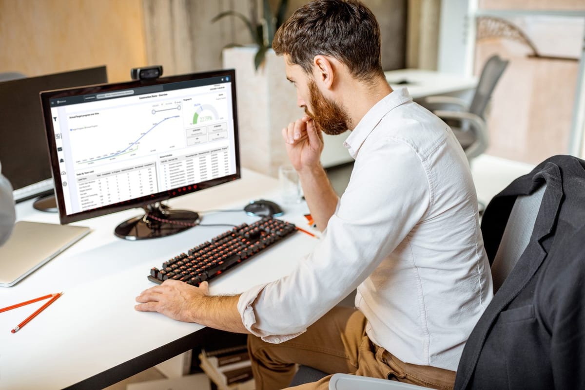 Manager reviewing progress analytics and an S-curve on a desktop to keep the project on track