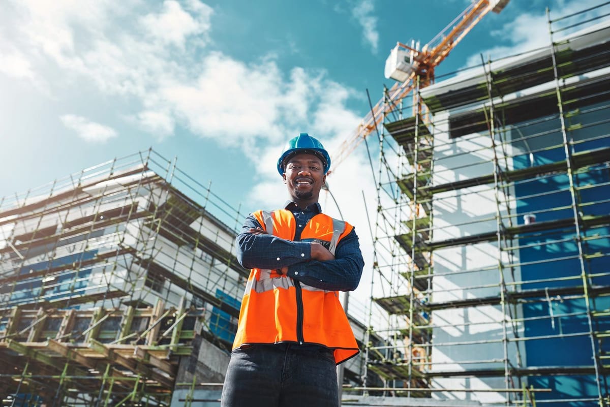 Smiling site worker in front of a scaffolded building on a project run to a live schedule