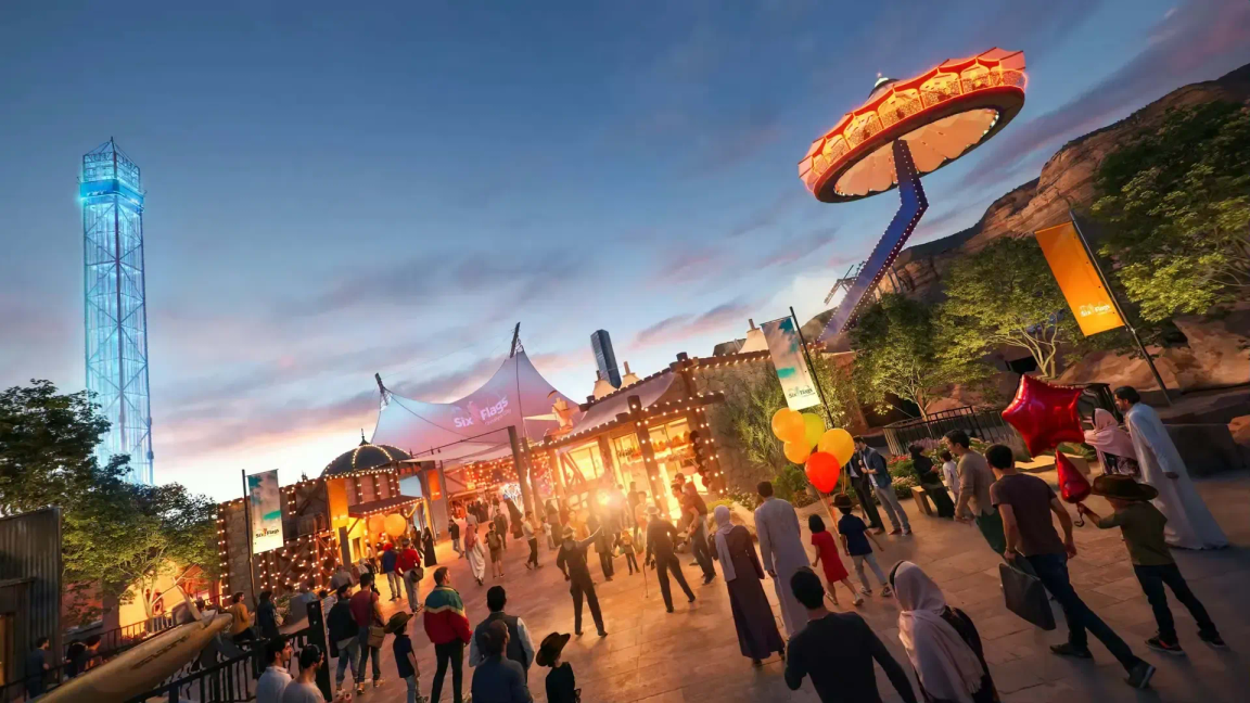 Dusk view of the Valley of Fortune area at Six Flags Qiddiya with visitors and rides
